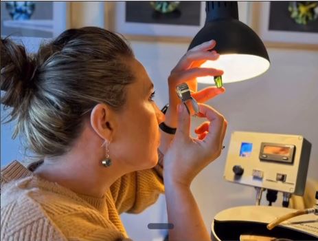 Alana Marcus inspecting a faceted sapphire under the workshop lamp